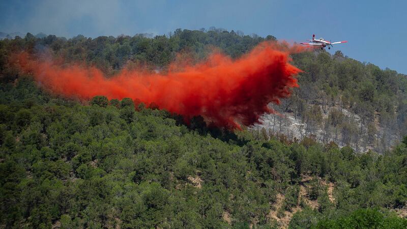 FILE - A plane drops fire retardant near the Lake Christine wildfire on July 4, 2018, in...