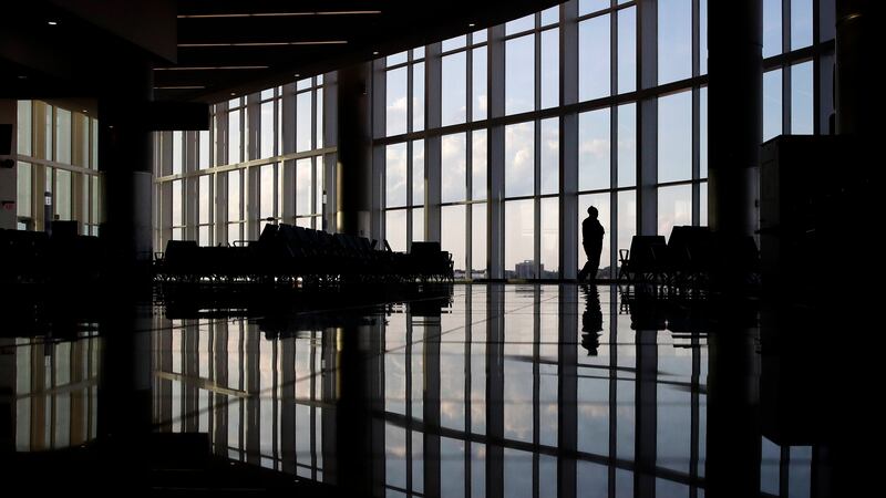 FILE - In this Monday, June 1, 2020 file photo, a woman looks through a window at a near-empty...