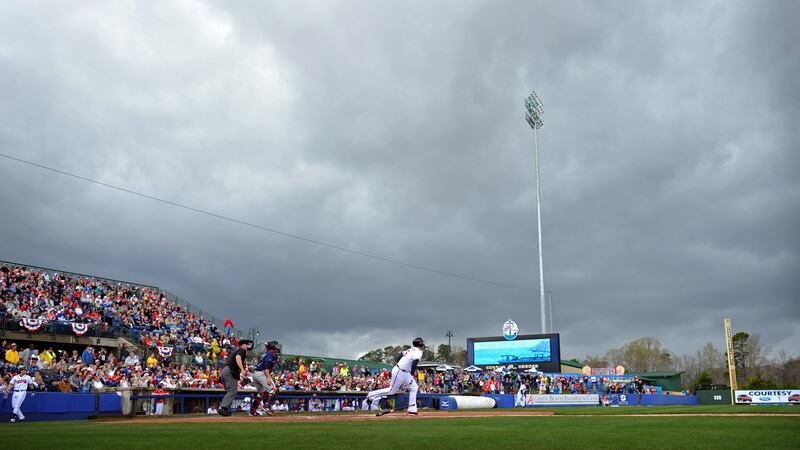 Atlanta Braves' Freddie Freeman runs toward first base as rain clouds move in before a...