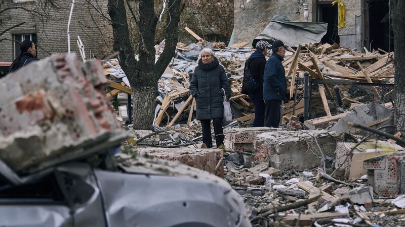 People stand in front of a heavily damaged building after a Russian attack in Sloviansk,...